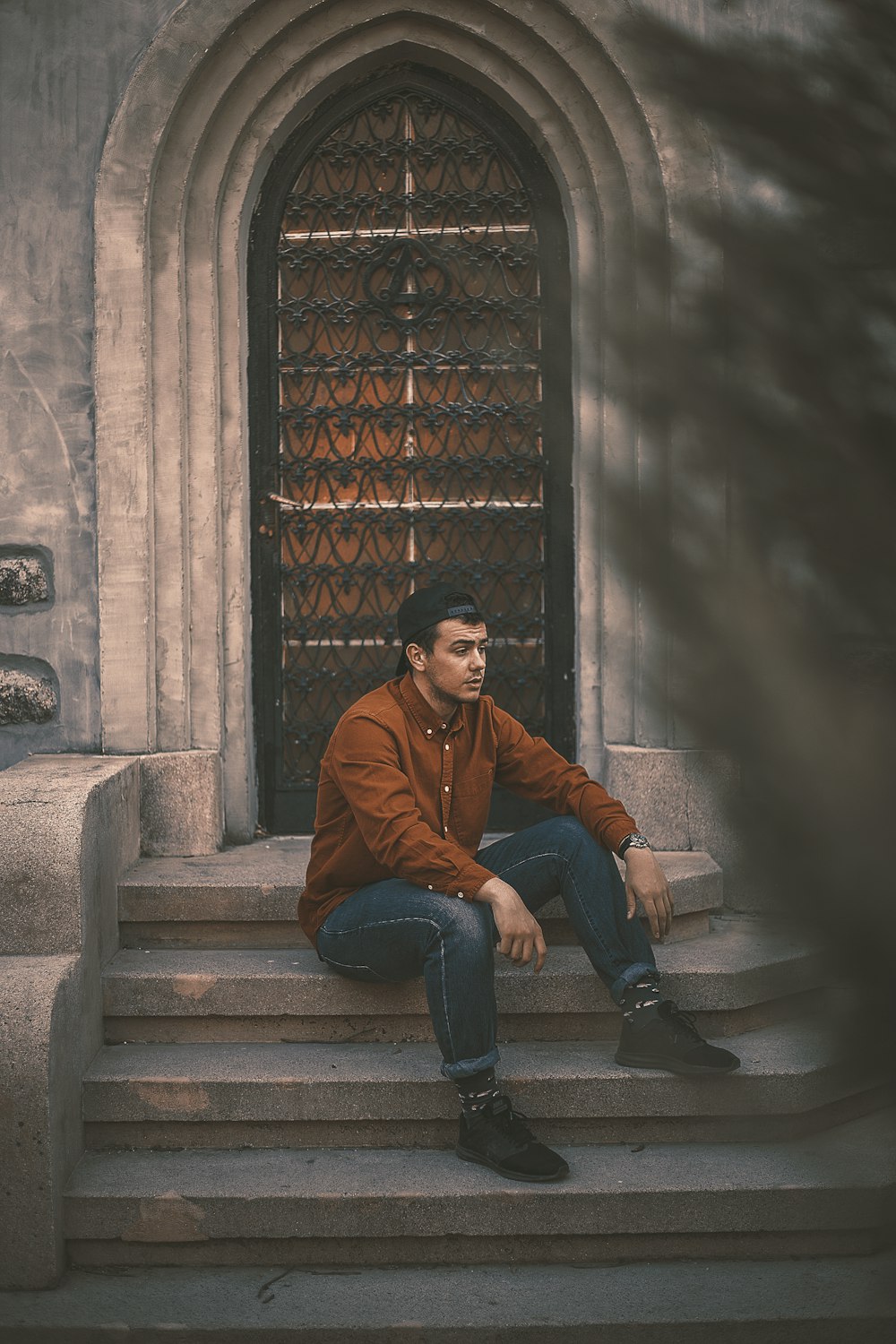 man in brown jacket and denim jeans sitting on top of stairs