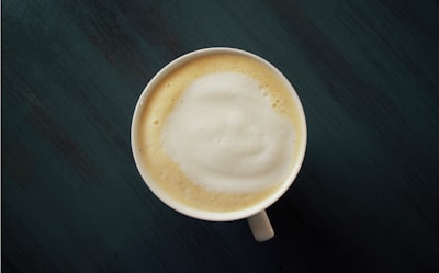 white ceramic mug on black surface latte zoom background