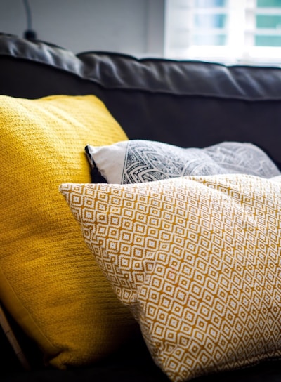 three assorted-color throw pillows on black sofa