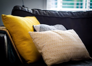 three assorted-color throw pillows on black sofa