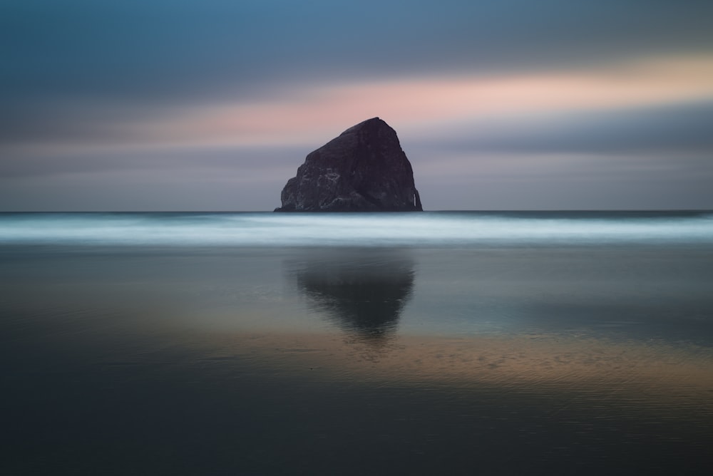 brown rock surrounded by body of water