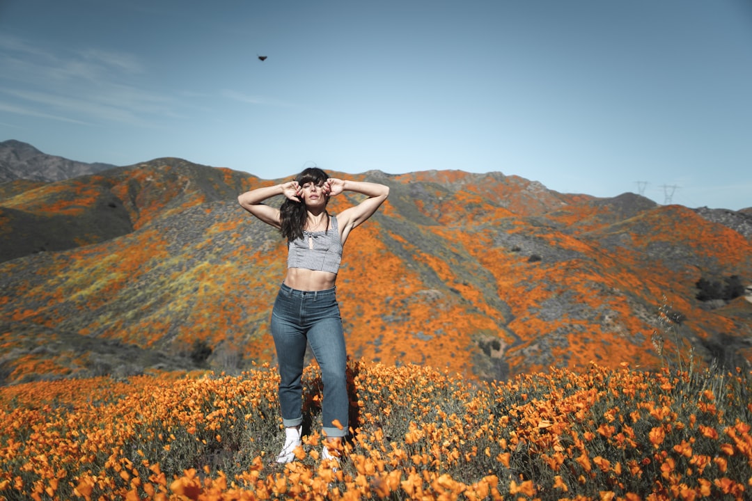woman in gray crop-top and denim bottom standing near orange flower field