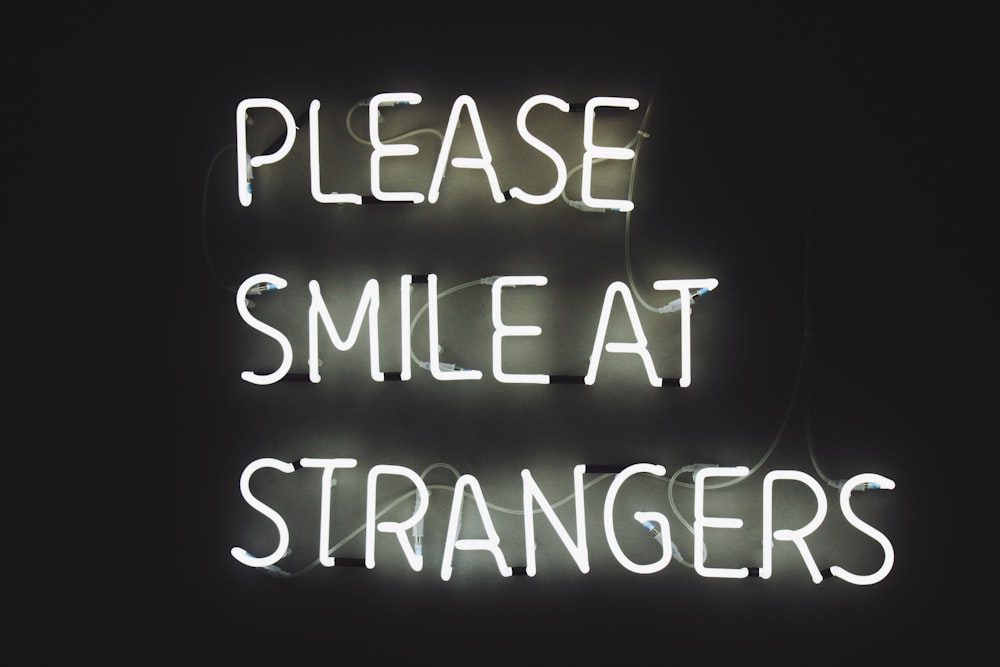 white LED light with text Please Smile at Strangers