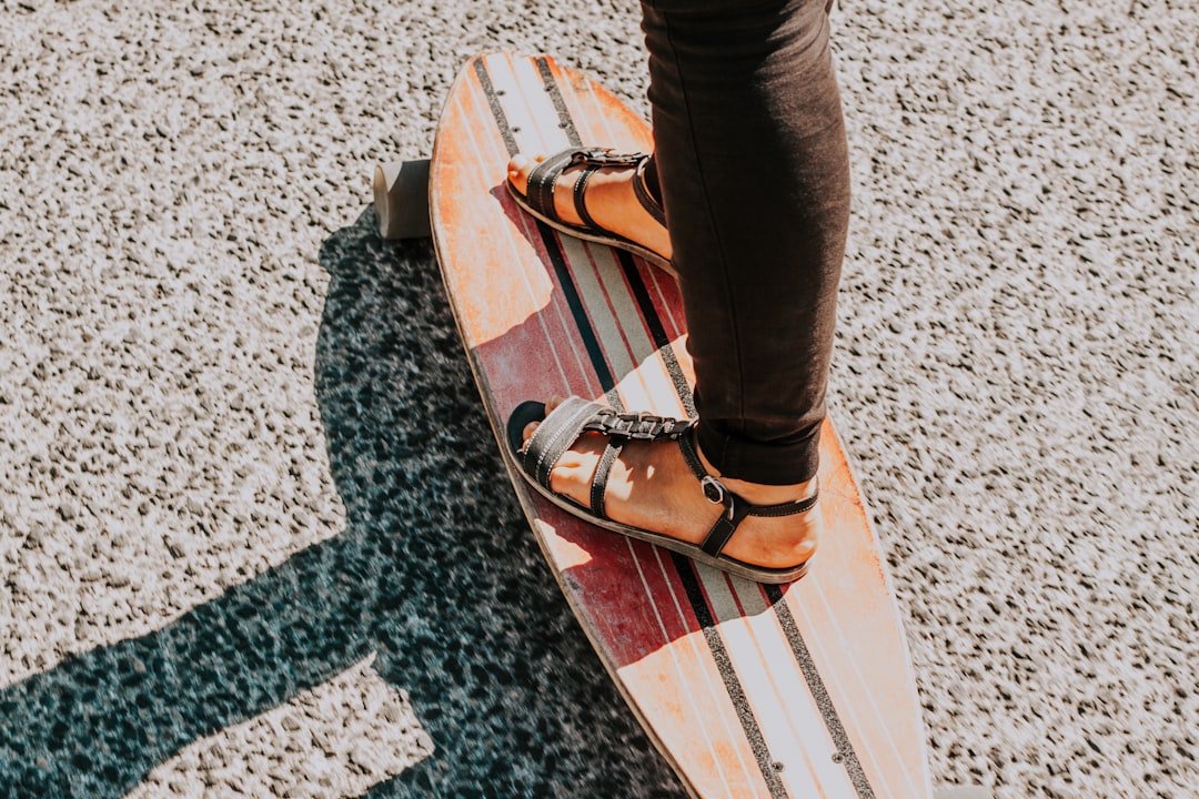 person wearing black sandals on long board