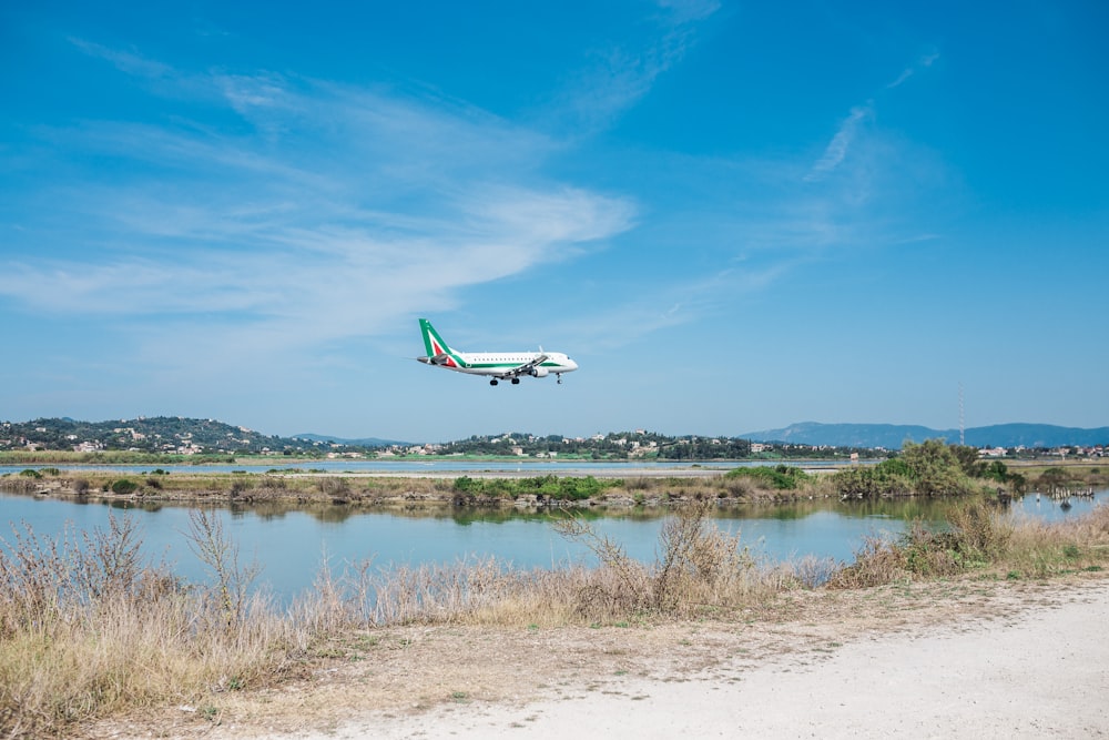 white and blue airliner flight near body of water