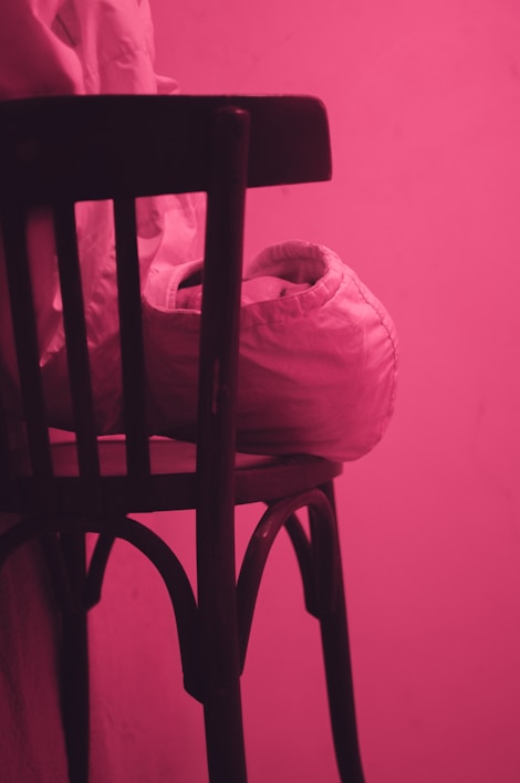 A cozy pastel pink vest draped over a wooden chair with soft natural light.