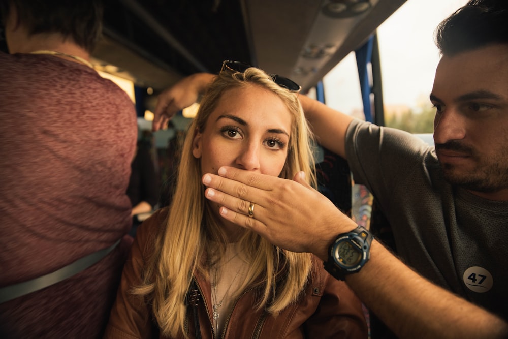 man covered the mouth of woman sitting inside vehicle