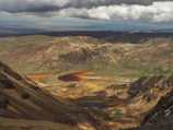 Group of tourists exploring colorful mineral-rich lagoons with mountains in the background