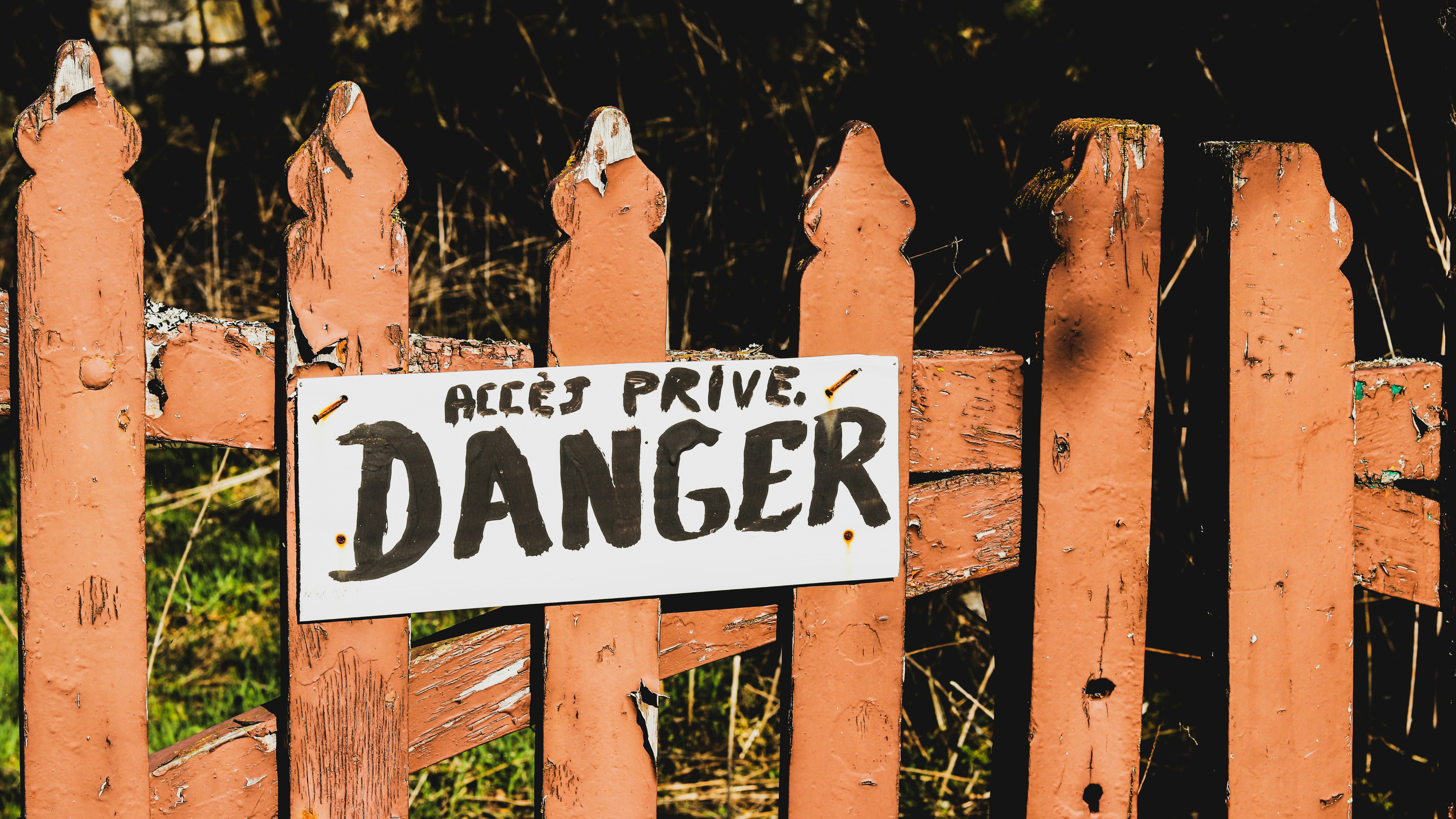 danger signage on brown wooden rail