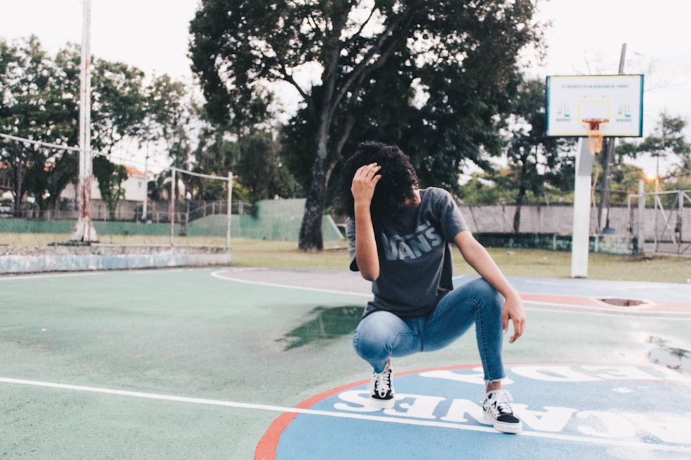 crouching woman wearing gray t-shirt on basketball court