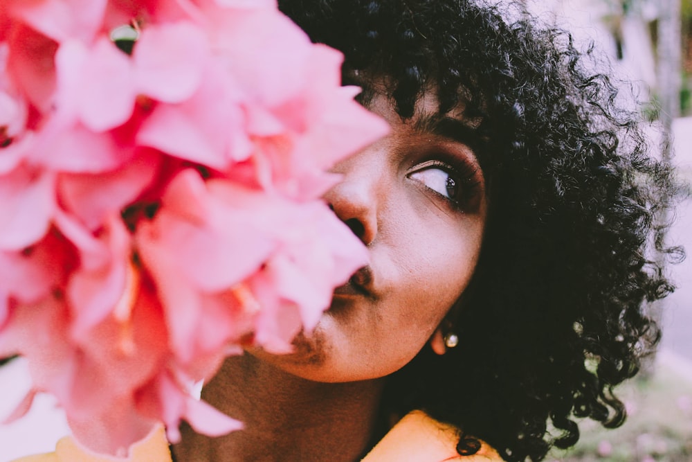 woman sniffing pink petaled flower