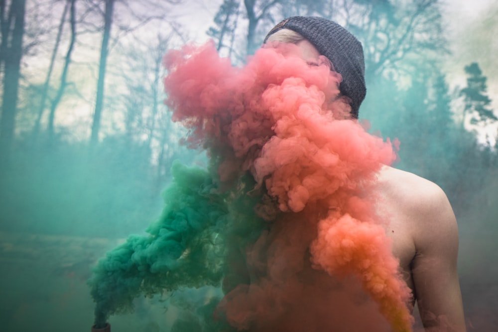 person blowing red and green smoke
