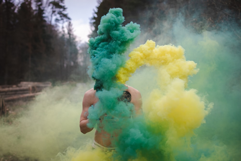 person standing in front of green and yellow smokes