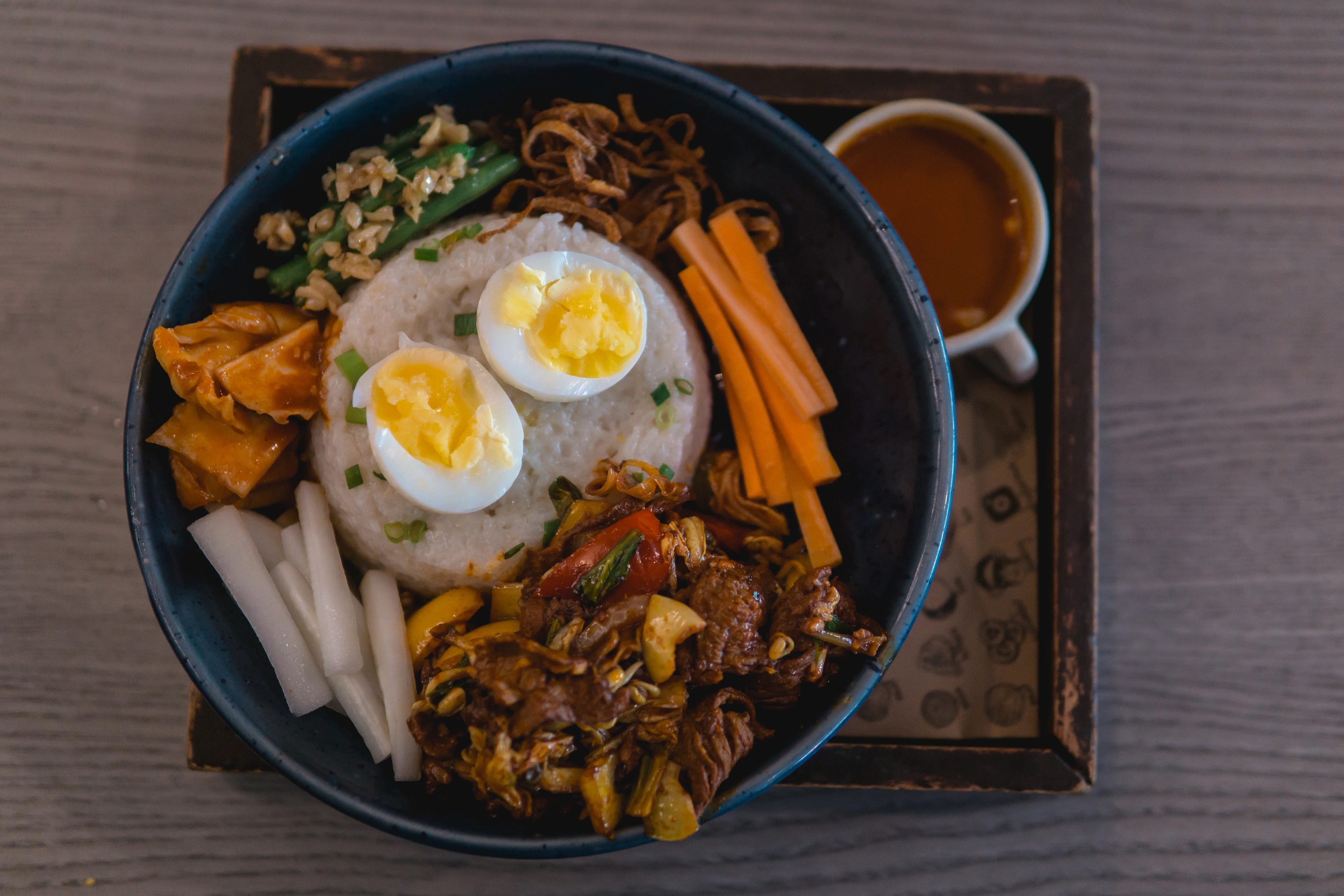 A rice plate loaded with a fried egg and pickles, seen up close