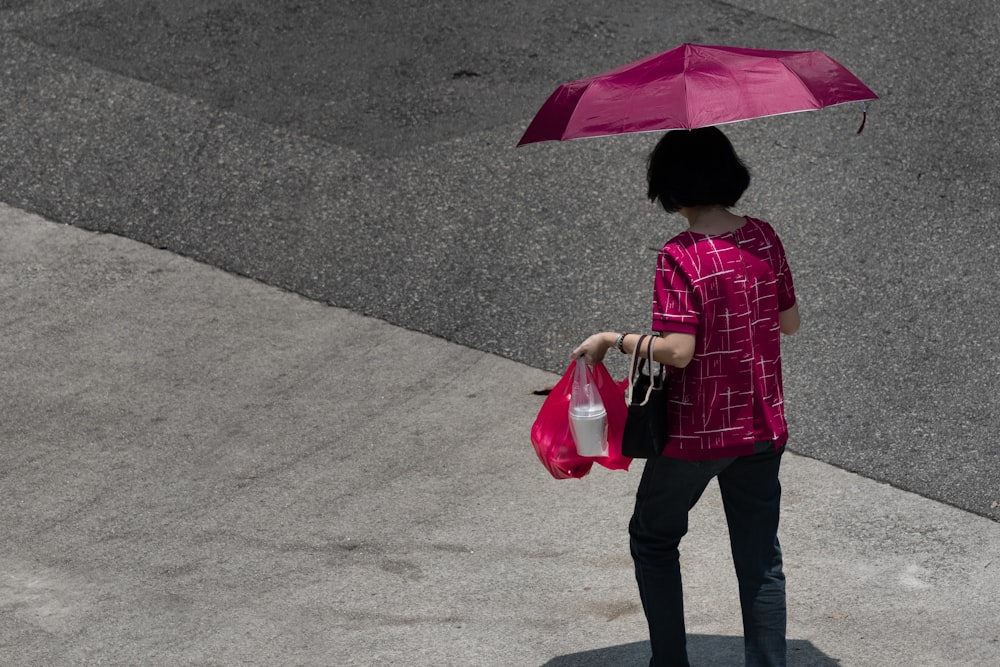 woman carrying bags while using umbrella