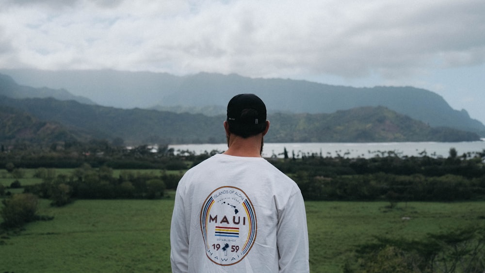 man wearing white sweat shirt with green field view near sea