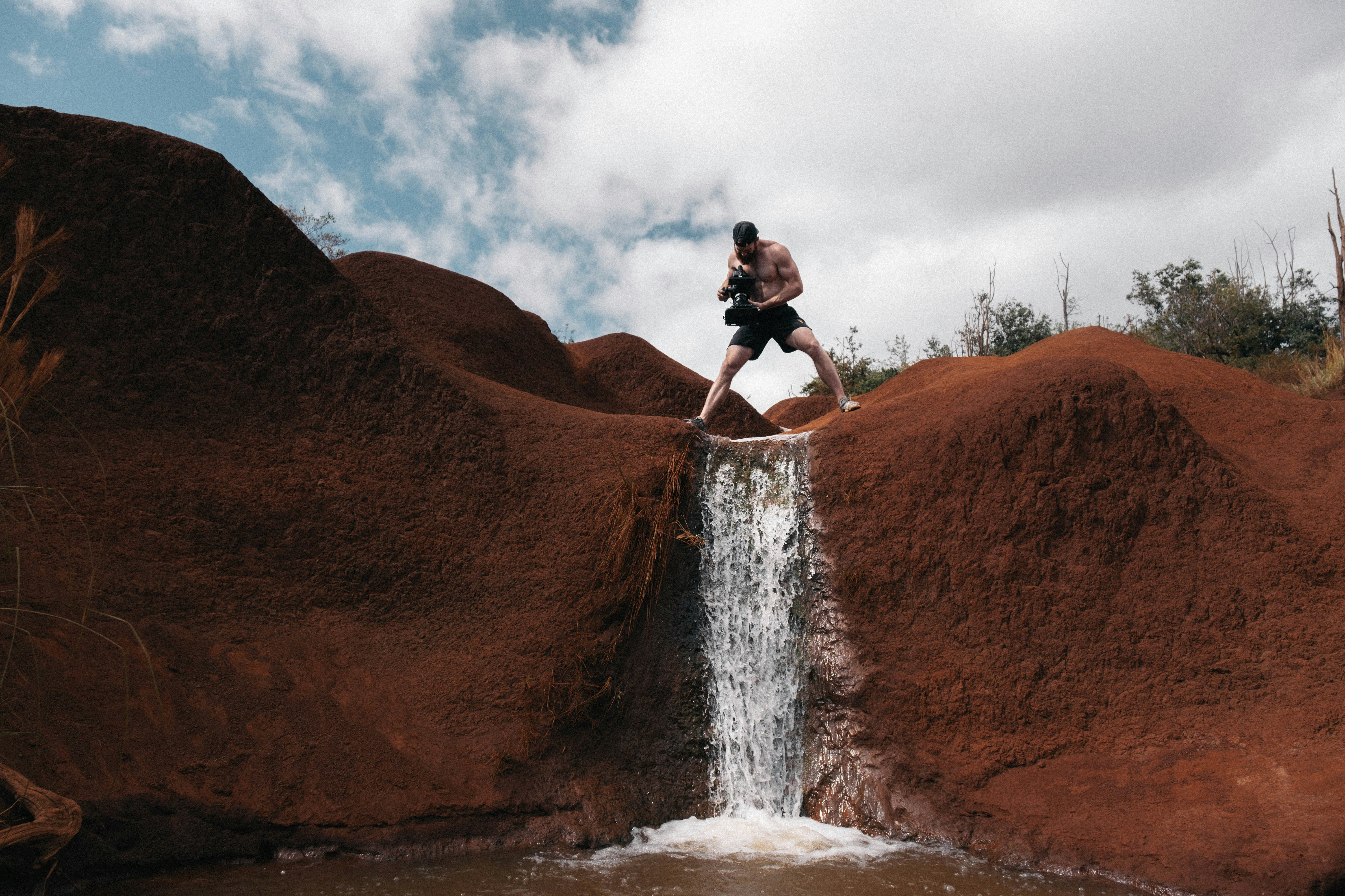 man wearing black shorts standing on waterfalls