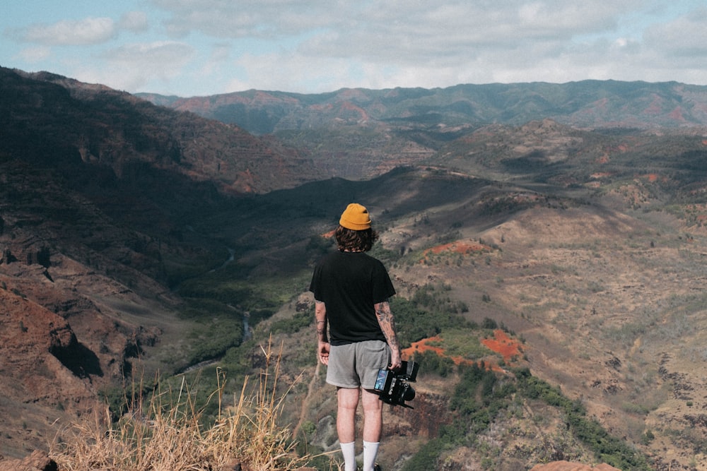 woman standing on cliff holding video camera