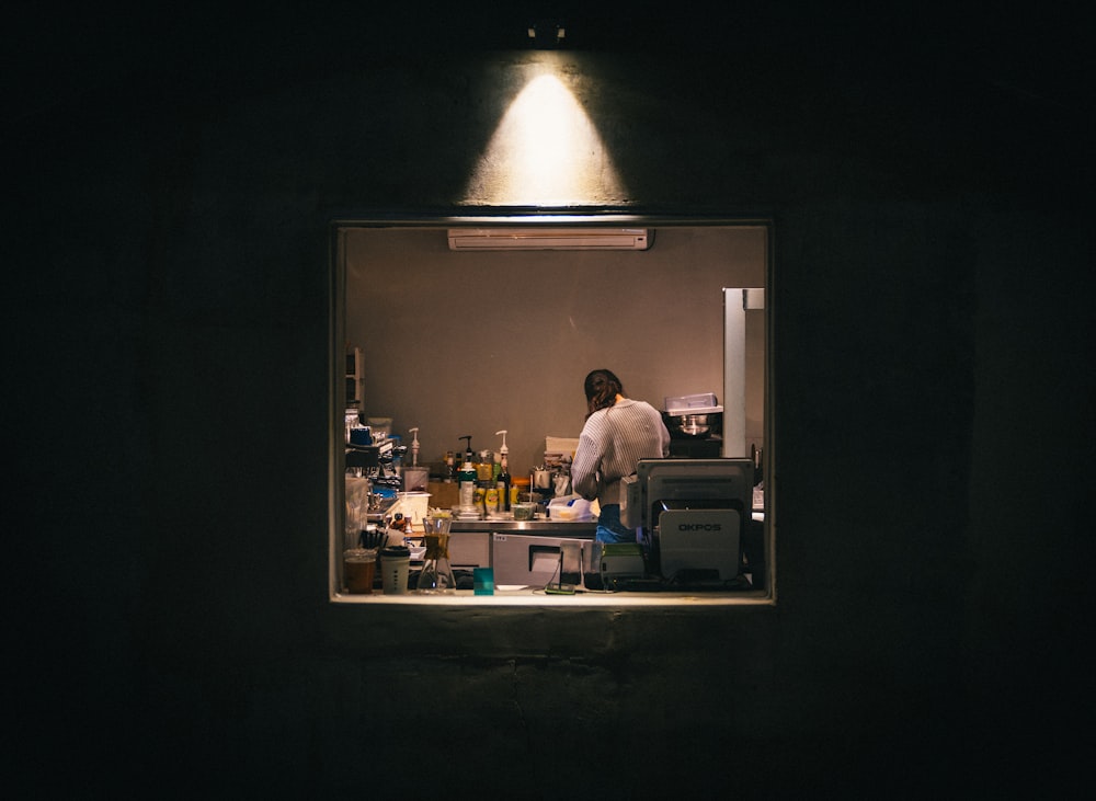 Foto con poca luz de la mujer de pie en el área de la cocina