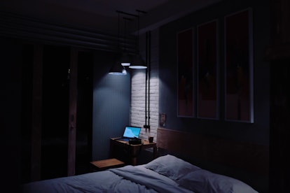 turned-on laptop computer on top of side table inside bedroom
