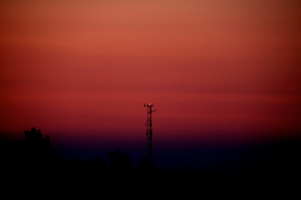 a red and purple sky with a tower in the foreground