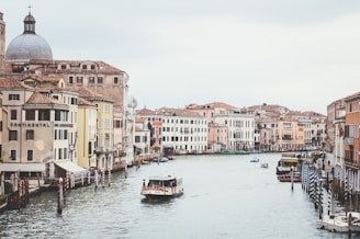 white passenger boat on river between houses
