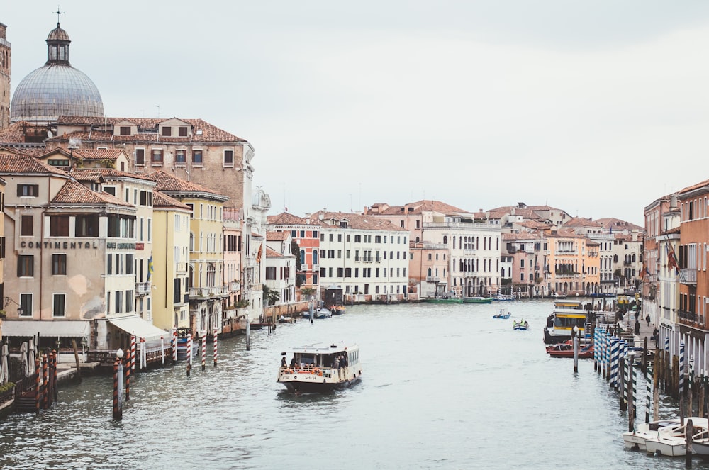 white passenger boat on river between houses