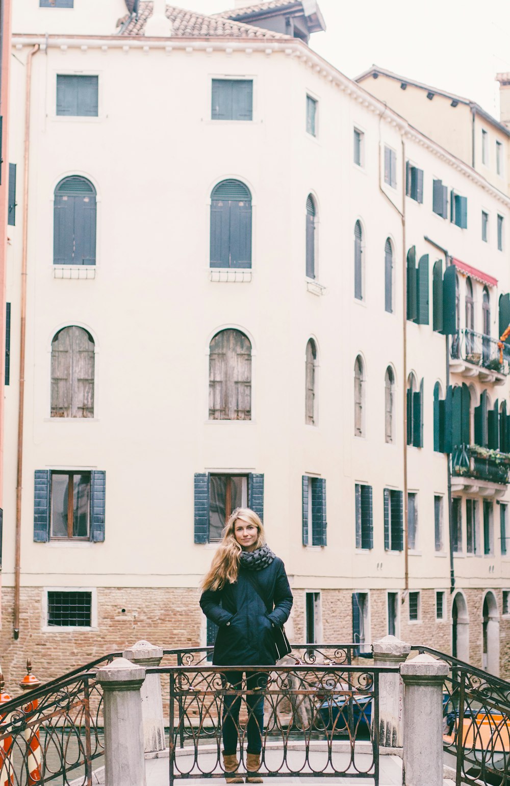 woman in bubble jacket standing on bridge near building