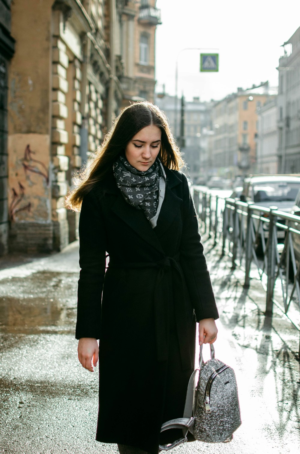 woman in black coat carrying bag standing beside bolsters