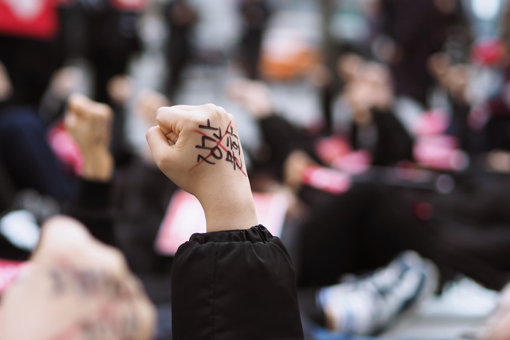 person wearing black long-sleeved top raising their hand