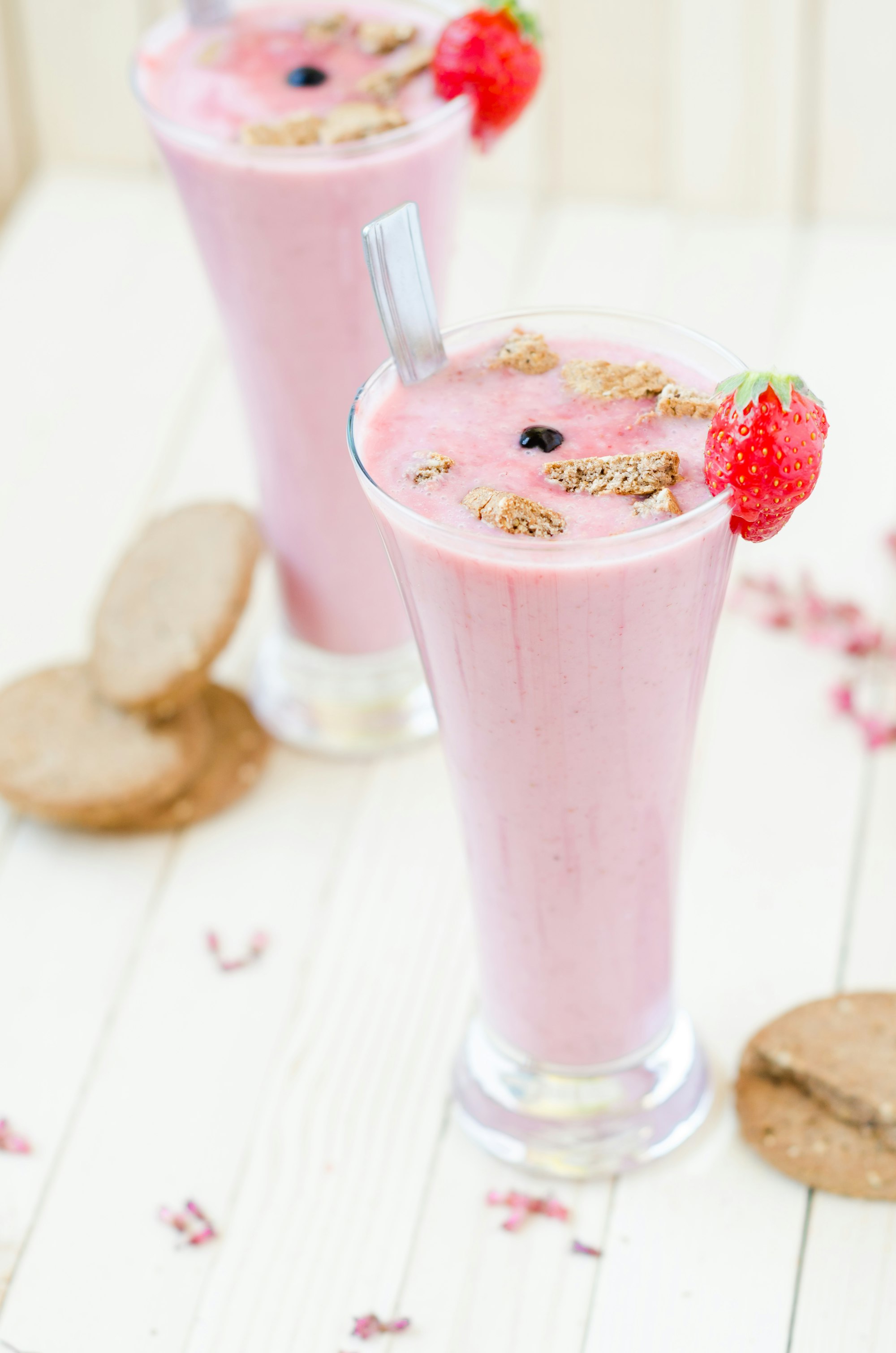 Pink Strawberry smoothie with brown cookies on light brown rustic table