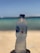 A plastic water bottle held up against a backdrop of a beach with sand and the ocean. The label on the bottle reads 'Nestlé Pure Life'. The bottle is slightly condensation-covered, suggesting a cool temperature.