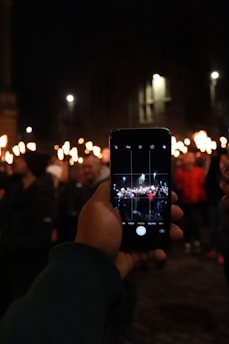 A concerned citizen holding a smartphone, capturing a street protest in San Miguel de Allende at sunset.