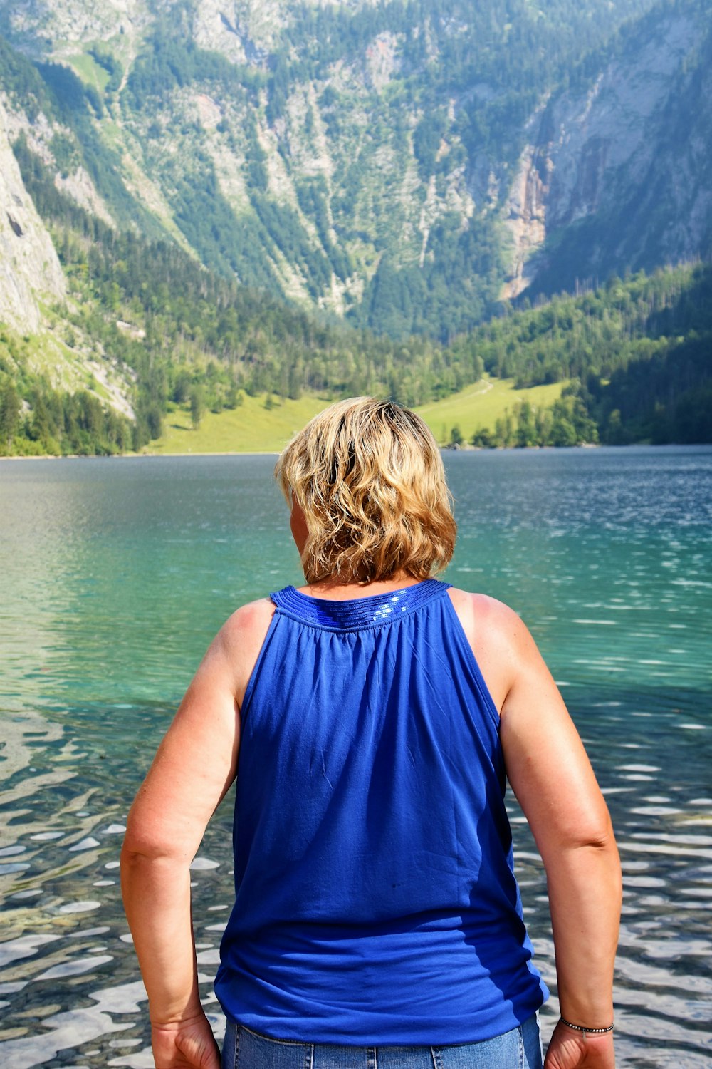woman standing near body of water fronting mountain