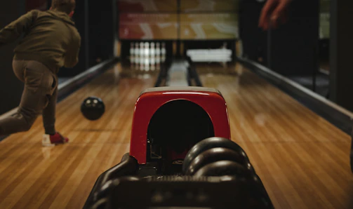A bowler releasing the ball with fierce concentration on his face.