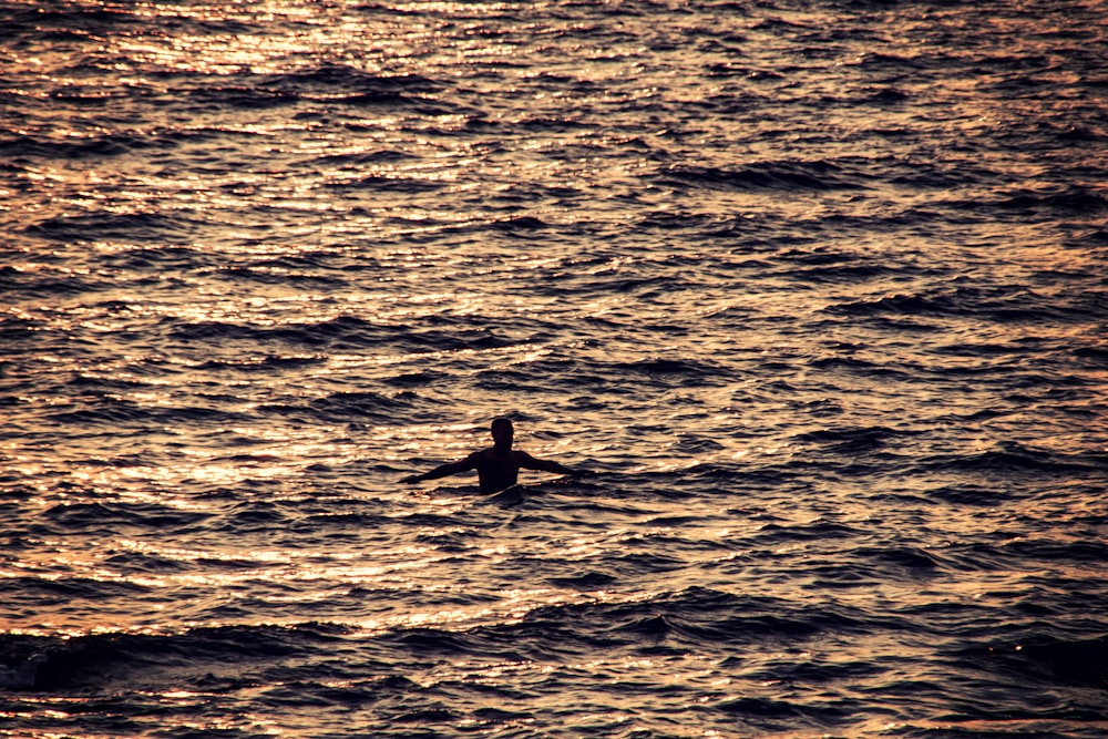 man swimming on sea