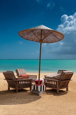 Quatre fauteuils sur la plage en journée protégés par un parasol