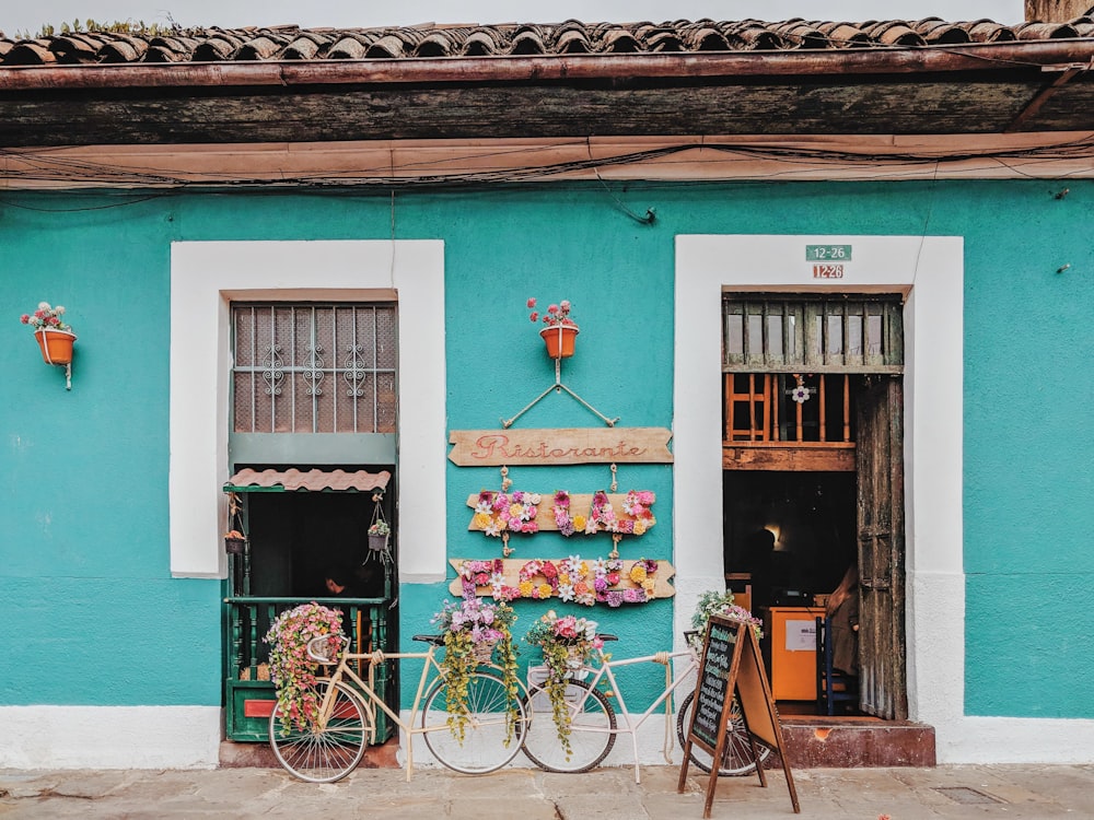 white bicycle parked beside teal painted concrete building during daytime