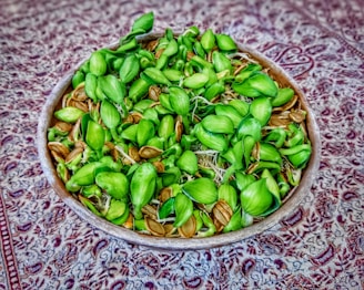 Close-up of fresh green moringa seeds spilling from a rustic burlap sack onto a wooden table.