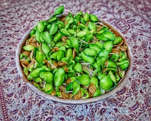 Small bowl of black kalonji seeds on a textured fabric surface.