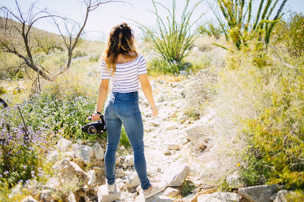 Femme debout sur un rocher gris face à des plantes vertes