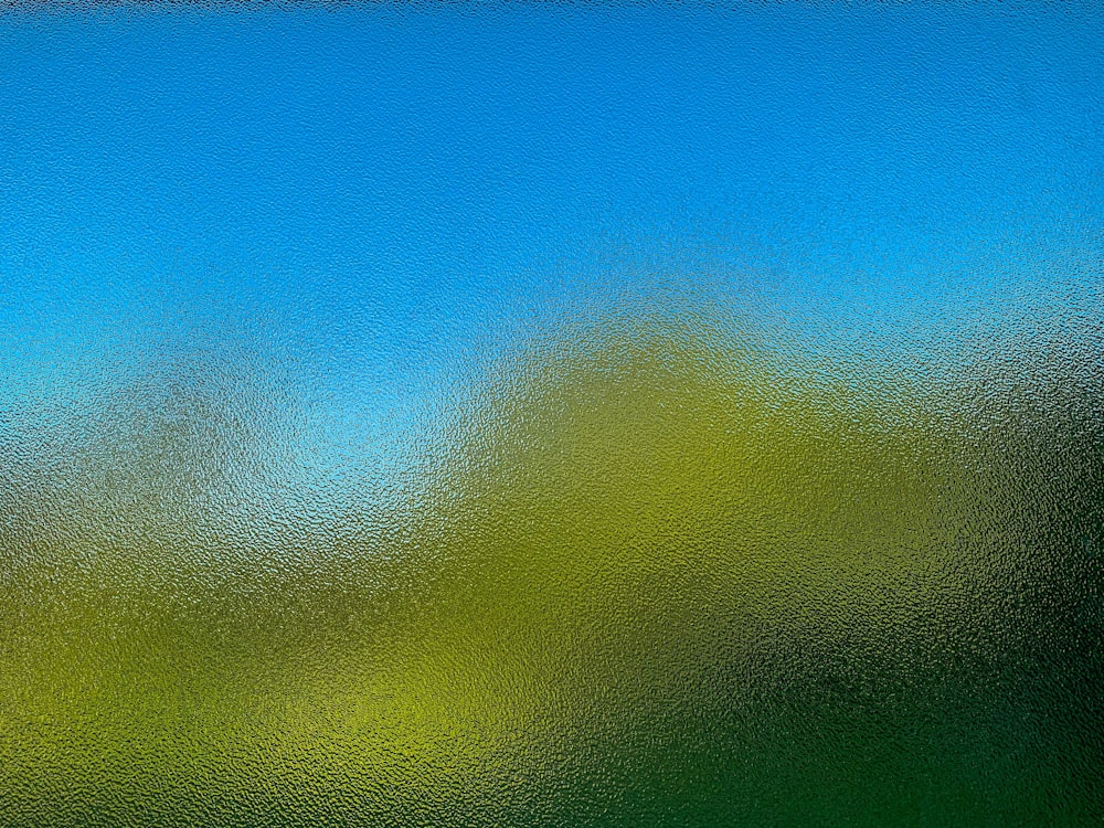 a blurry image of a blue sky and green grass