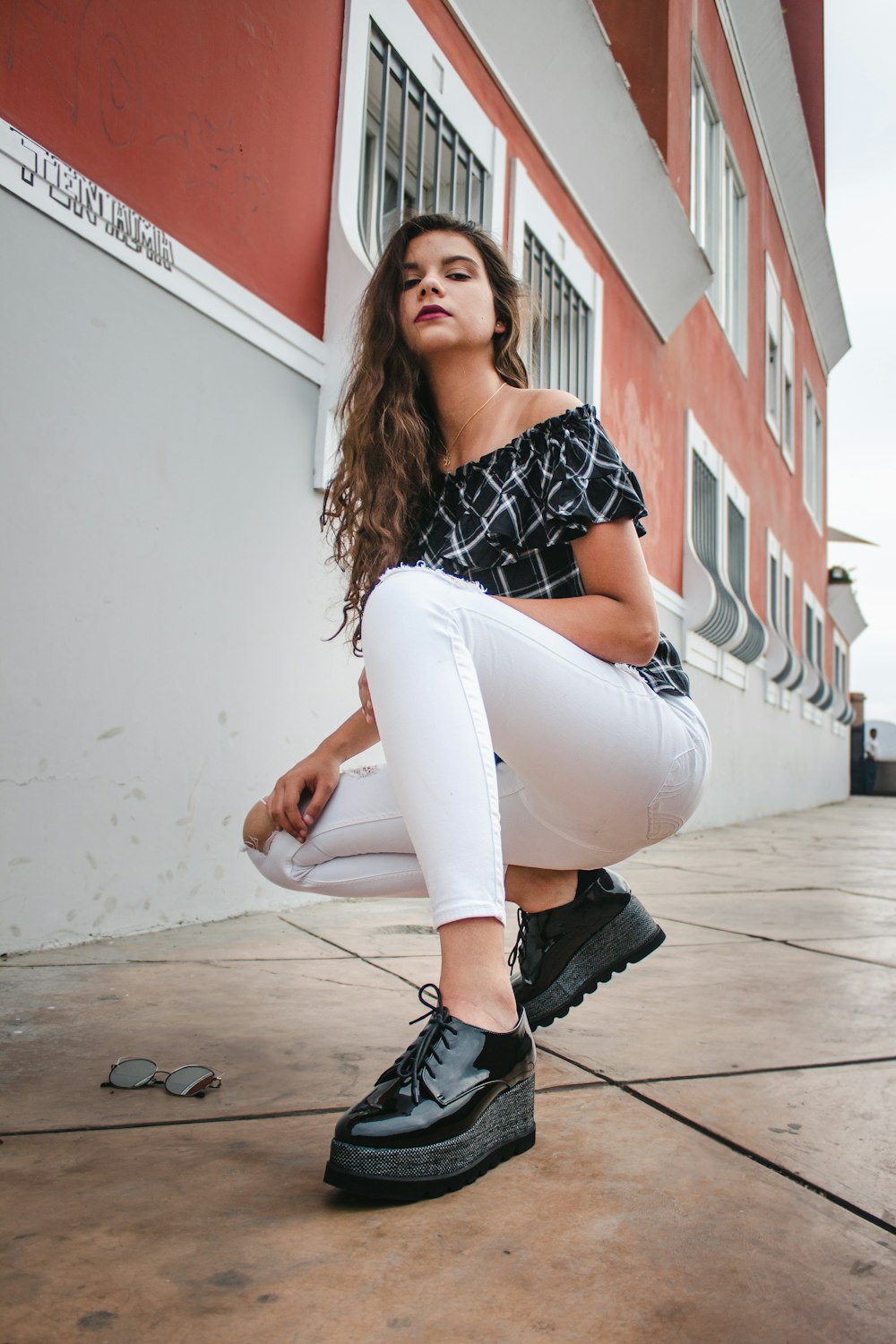 woman kneeling on sidewalk during daytime