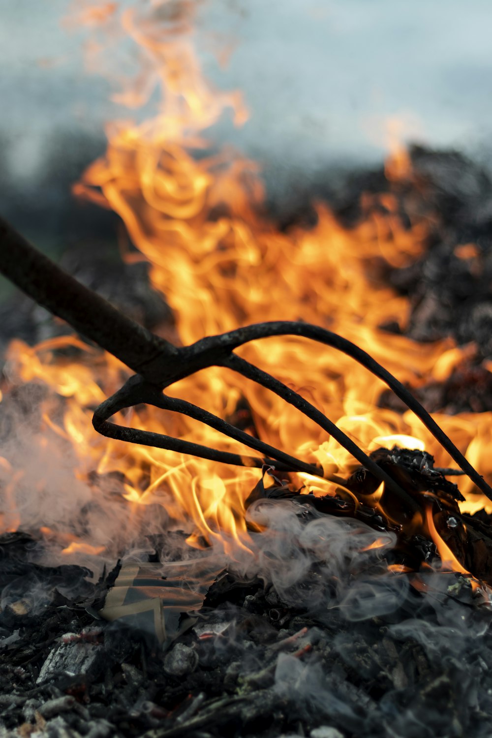 garden fork near burning wood during daytime