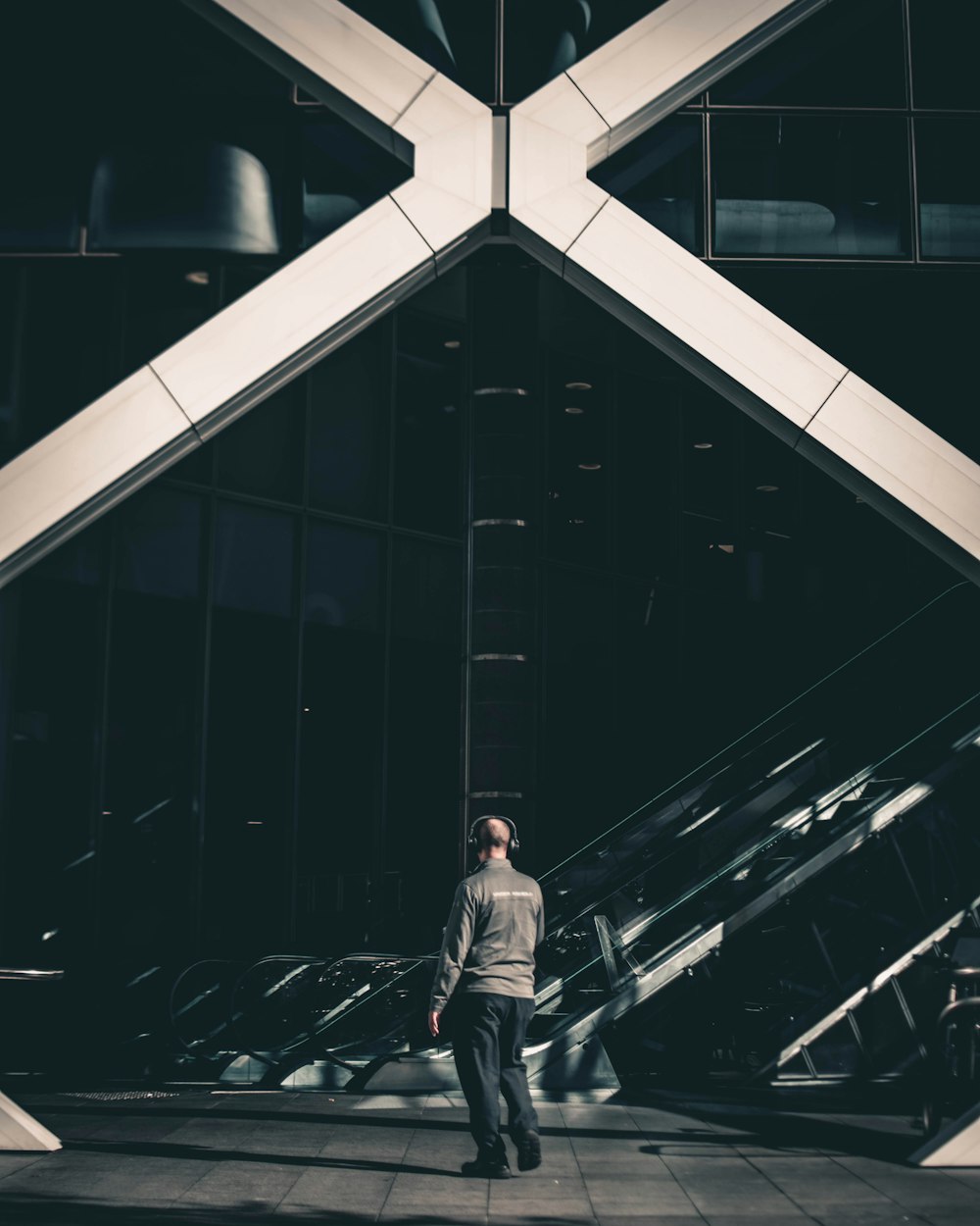 woman in gray sweater standing in front of glassy building