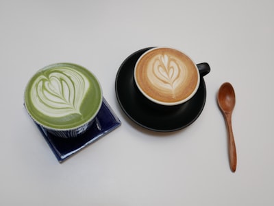 two brown and green chocolate foams on cups latte google meet background