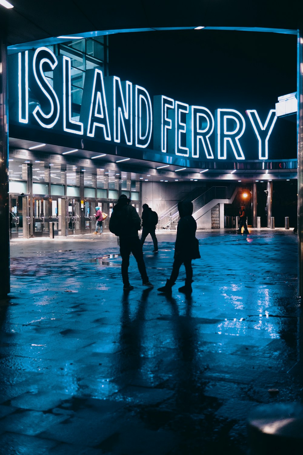 silueta de tres personas de pie cerca del ferry de la isla por la noche