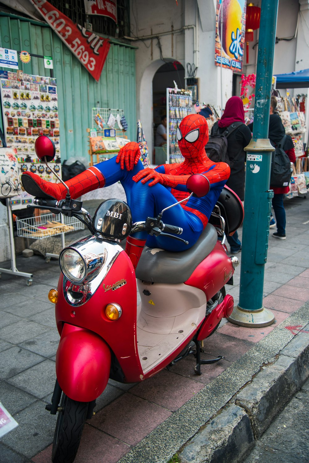 Spider-Man sitting on the motor scooter