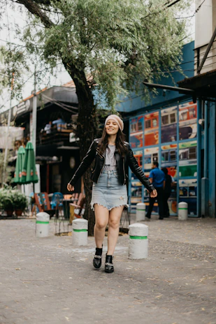 A young woman walking city streets confidently, carrying a sleek black yume shoulder bag.
