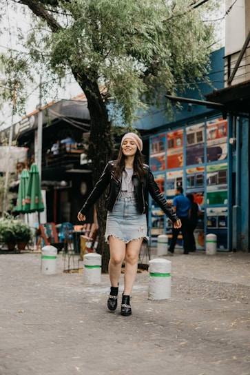 Young woman wearing casual chic outfit walking confidently through an urban street with soft pastel tones.